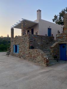 kamienny dom z niebieskimi drzwiami i kamienną ścianą w obiekcie Charming Vourkari Stone Home 3 - Minutes from Port w mieście Vourkari