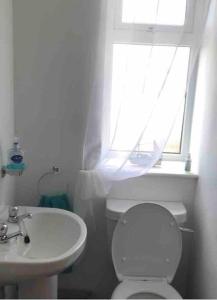 baño con aseo y lavabo y ventana en Millstreasm en Pollachar