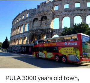 a red double decker bus parked in front of the coliseum at Apartmani Val in Pula