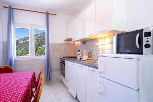 cocina con electrodomésticos blancos, mesa y ventana en Apartments Bodlović, en Hvar