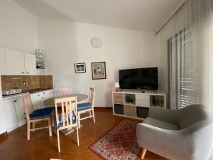 een woonkamer met een tafel en stoelen en een televisie bij Apartments Natasa in Punat