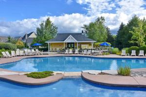 a large swimming pool with chairs and a house at Executive Town Home-Mountain View-Historic Snowbridge Village, Walking Distance to the Resort in Collingwood