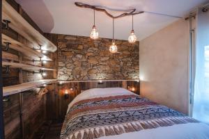 孔布盧的住宿－Le GoOfy, Centre, Navettes pistes ski Combloux，一间卧室设有一张床和石墙