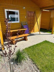 een houten picknicktafel op een veranda van een huis bij Domki Milka in Ustka