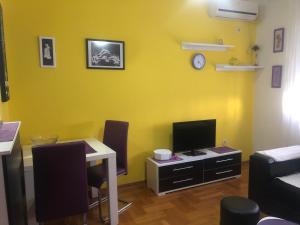 Dieses gelbe Zimmer verfügt über einen Schreibtisch mit einem Computer und einen TV. in der Unterkunft Apartman Tanjuška in Podgorica