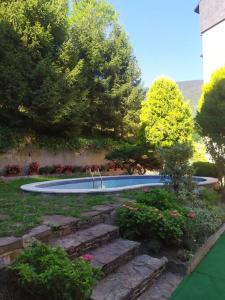 un giardino con piscina e alcuni alberi e fiori di Dúplex abuhardillado con vistas y parking a Vielha