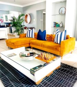a living room with a yellow couch and chess board at Summerstrand Boutique Beach Apartment in Summerstrand