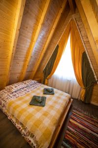 uma cama num quarto de madeira com uma janela em Catunul din Podei A-Frame em Dragoslavele