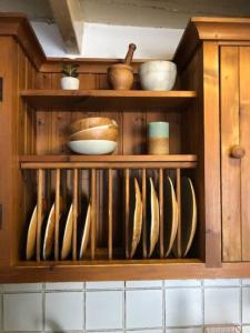 a wooden cabinet with bowls and utensils in it at Fishermens cottage with secret garden in Port Isaac