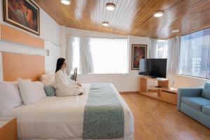 Suites Coben Apartamentos Amueblados في مدينة ميكسيكو: امرأة تجلس على سرير في غرفة النوم