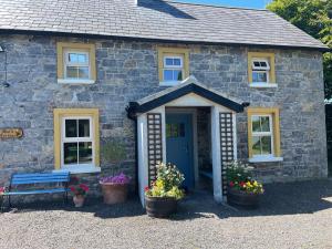 een klein stenen huis met een blauwe deur en bloemen bij Mai's Cottage Suite - Charming Holiday Rental in Kilmallock