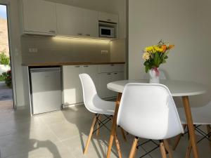 eine Küche mit einem Tisch, weißen Stühlen und einer Vase aus Blumen in der Unterkunft Yannis Apartments in Ammoudara