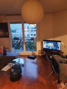 uma sala de estar com uma televisão de ecrã plano e um sofá em superbe appartement em Châtillon