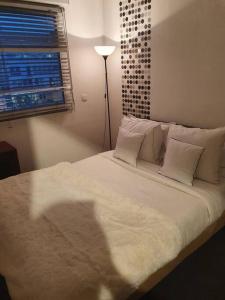 uma cama com lençóis brancos e almofadas num quarto em superbe appartement em Châtillon