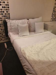 1 cama grande con sábanas y almohadas blancas en superbe appartement, en Châtillon
