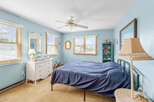 a bedroom with blue walls and a bed and a ceiling fan at Catch 'n' Cook Cottage in Frisco