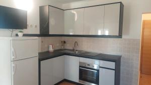 a kitchen with white cabinets and a sink and a refrigerator at Apartments Donadic I, Caska in Novalja