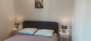 a bedroom with a bed with two lamps on two tables at Apartments Donadic I, Caska in Novalja