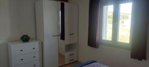 a bedroom with a dresser and a window at Apartments Donadic I, Caska in Novalja