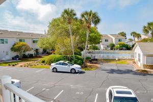 ein weißes Auto auf einem Parkplatz mit Palmen geparkt in der Unterkunft Sweet Spot at Woodland Shores in Destin