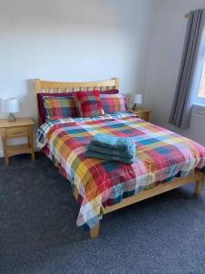 a bedroom with a bed with a colorful blanket at Tullybrannigan Cottage Newcastle in Newcastle