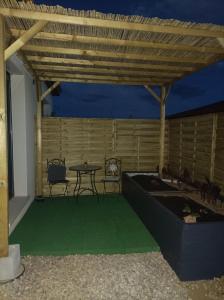 patio con tavolo e sedie sotto un tetto in legno di Chambre studio aménagé a Cers