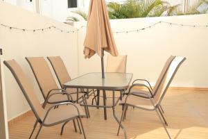 a glass table with chairs and an umbrella at Casa familiar 3 habitaciones Playa del Carmen in Playa del Carmen