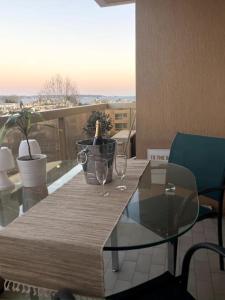 einen Glastisch mit zwei Weingläsern auf dem Balkon in der Unterkunft Appartement cosy vue mer, 5min à pied de la plage, parking in Vallauris