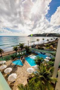 einen Blick über einen Pool mit Sonnenschirmen und das Meer in der Unterkunft Apart_Hotel Ponta negra in Natal