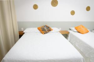 two beds in a room with white and orange pillows at POUSADA CAJU DO MATO in Prado