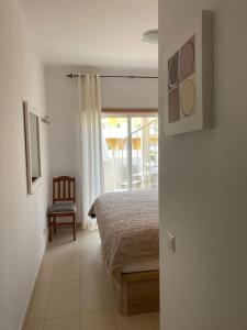 a bedroom with a bed and a chair and a window at Royal Cabanas Gold penthouseT2 in Conceição