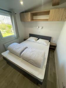 Una cama con sábanas blancas y almohadas en un dormitorio en Cozy Chalet at the Beach in Petten, Netherlands, en Petten