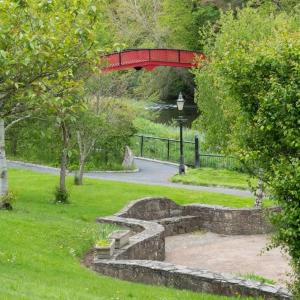 a red bridge over a park with a stone path at Riverside Lodge in Carlow