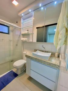 um banheiro com uma pia, um vaso sanitário e um espelho em todo climatizado, 2 quartos e piscina na 706 sul em Palmas