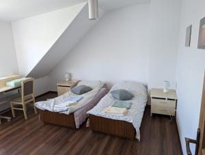 two beds in a room with a desk and a table at Apartament Osak in Stare Juchy