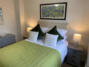 sypialnia z zielonym i białym łóżkiem z poduszkami w obiekcie Comfortable new home in Isleham w mieście Ely