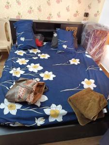 a bed with a blue comforter with white flowers on it at Joy House - 1 bhk Cozy entire house in Ooty
