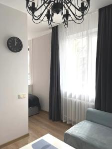 a bedroom with a chandelier and a bed and a clock at Apartamentai centre in Klaipėda