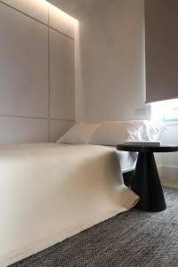 a white bedroom with a bed and a table at Hidden GEM-Renovated 2023-Studio Garibaldi-perfect for Romantic couples-Best of the Best in Olbia