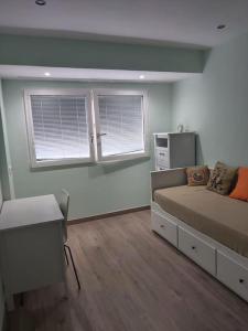 a bedroom with a bed and a desk and two windows at Modern flat at Garbinet with WiFi in Alicante