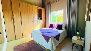 a bedroom with a bed with purple sheets and a window at Recanto Jade in Taubaté