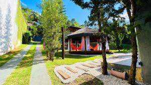 a garden with a house with a sign in the grass at Recanto Jade in Taubaté