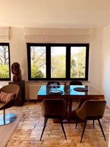 ein Wohnzimmer mit einem Tisch, Stühlen und Fenstern in der Unterkunft Appartement 1 chambre - LAKE SIDE HOUSE in Rixensart
