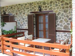 a patio with a table and chairs and a stone wall at ΠΑΝΣΙΟΝ ΑΓΓΕΛΟΣ ΜΑΝΑΡΗ in Ouranoupoli