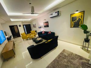 伊斯兰堡High Rise Presidential Suite in Elysium Opp Centaurus的客厅配有黑色沙发和黄色椅子