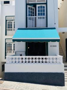 una tienda frente con un toldo azul en un edificio en EL JORADO en Tamaduste
