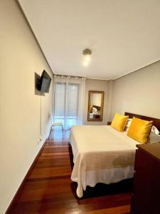 una camera da letto con un letto con cuscini gialli e una TV di Apartamento Somocuevas a Liencres