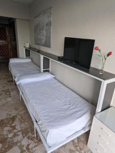 a room with three beds and a flat screen tv at LOFT CASTILLO SANTA CLARA Torremolinos in Torremolinos