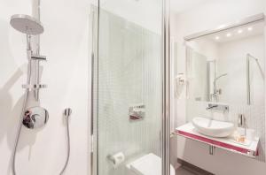 a white bathroom with a shower and a sink at Apartament Soleil III in Gdańsk