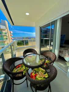 a table and chairs with a bowl of food on a balcony at Temporada Cabo Frio - Braga in Cabo Frio